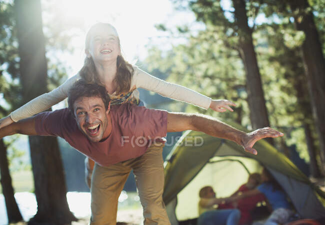 Exuberant father carrying daughter on back in woods — Stock Photo