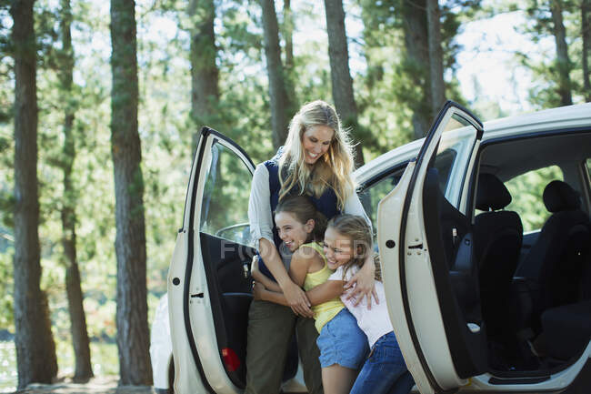 Mother hugging daughters outside car in woods — Stock Photo