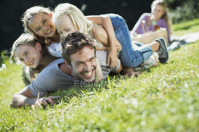 Daughters tackling father in grass — Stock Photo