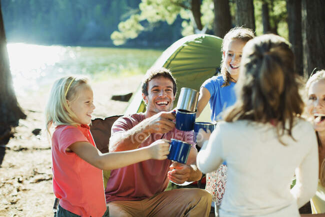 Sorrindo família brindar canecas no parque de campismo — Fotografia de Stock