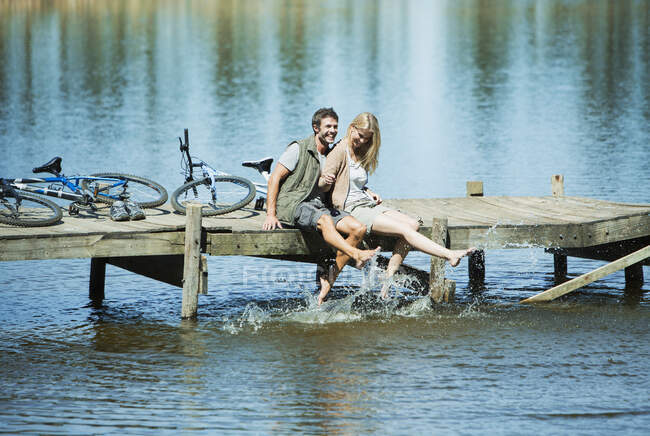 Пара на причале, брызгающая ногами в озере — стоковое фото