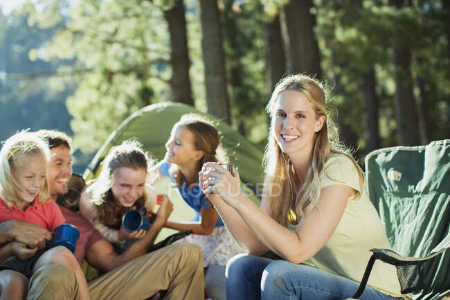 Famille souriante relaxante au camping dans les bois — Photo de stock
