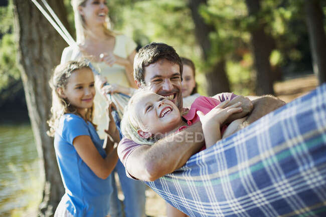 Família feliz que põe na rede em florestas — Fotografia de Stock
