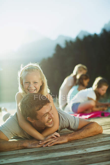 Smiling father and daughter laying on dock — Stock Photo