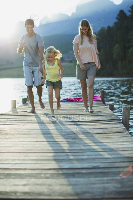 Familie läuft auf Steg über See — Stockfoto