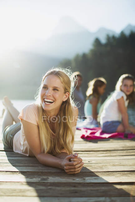 Woman laying on dock and laughing — Stock Photo