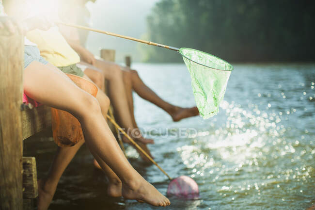 Family on dock with fishing nets dipping feet in lake — Stock Photo
