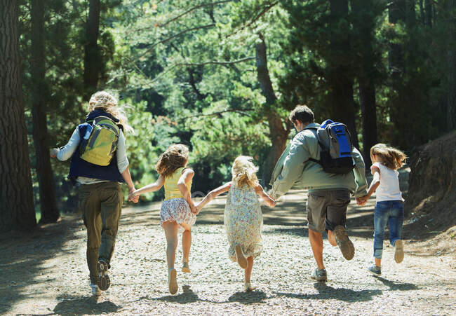 Сім'я тримається за руки і бігає в лісі — стокове фото