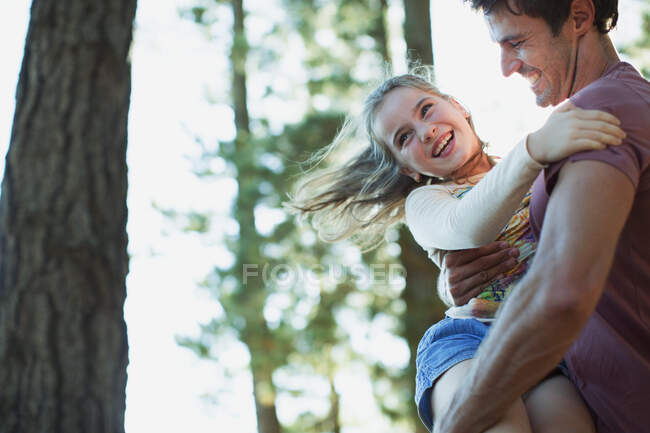 Padre girando hija en el bosque - foto de stock