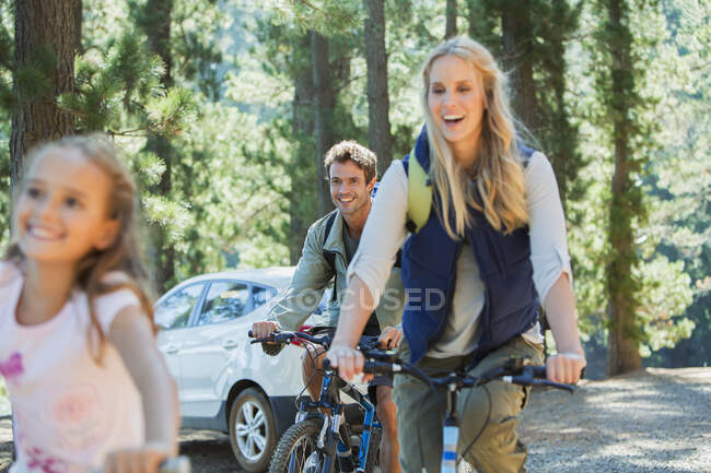 Sorrindo família montando bicicletas de montanha na floresta — Fotografia de Stock