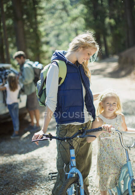 Mãe e filha sorridente com bicicletas na floresta — Fotografia de Stock
