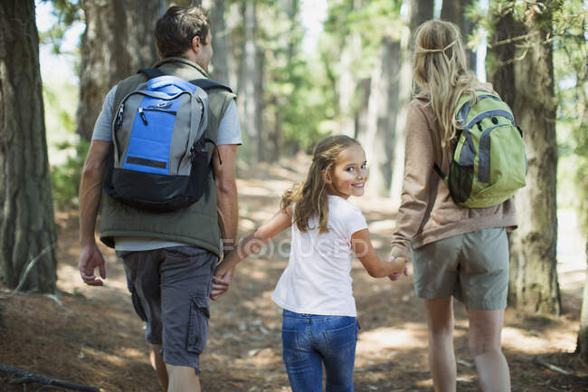 Smiling girl hiking with parents in woods — Stock Photo