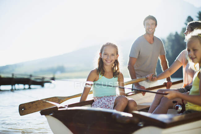 Família sorridente em barco a remos no lago — Fotografia de Stock