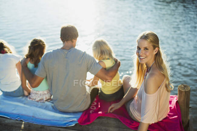 Mulher sorridente com a família na doca sobre o lago — Fotografia de Stock