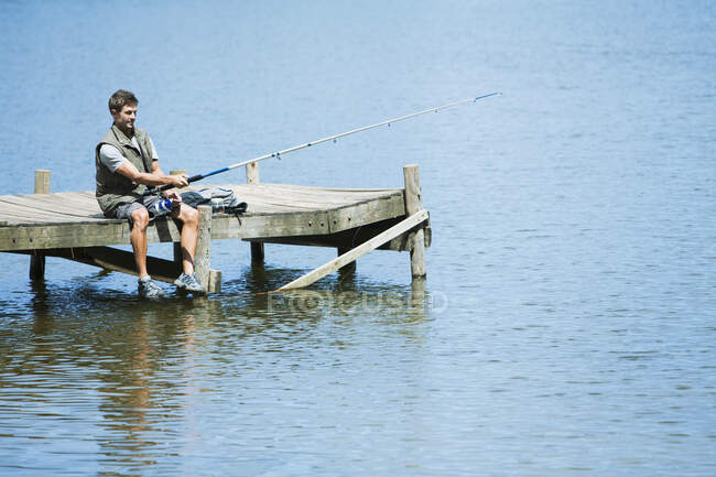 Mann fischt von Steg über See — Stockfoto