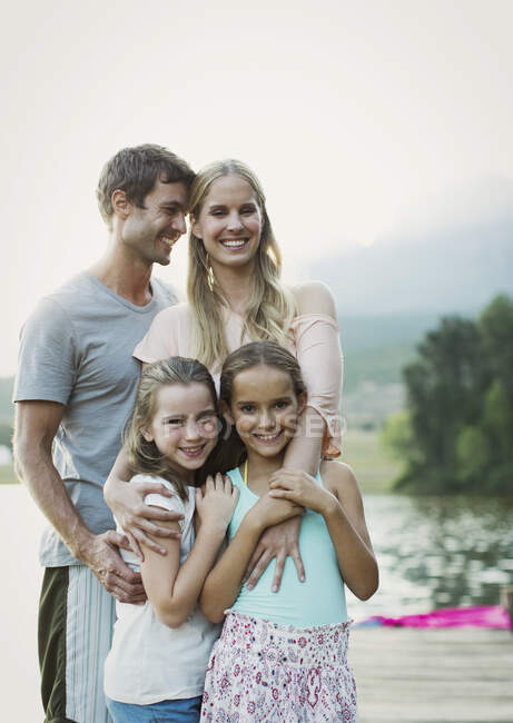 Lächelnde Familie auf Dock über dem See — Stockfoto