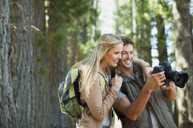 Couple looking at digital camera in woods — Stock Photo