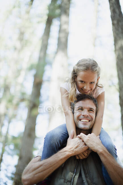Lächelnder Vater trägt Tochter im Wald auf Schultern — Stockfoto