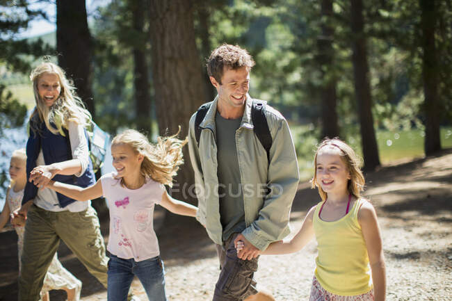 Sorrindo família de mãos dadas e caminhando na floresta — Fotografia de Stock