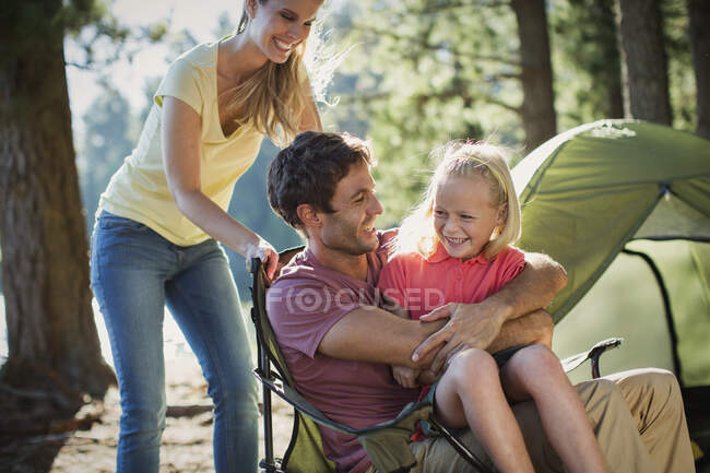 Família sorridente no acampamento na floresta — Fotografia de Stock