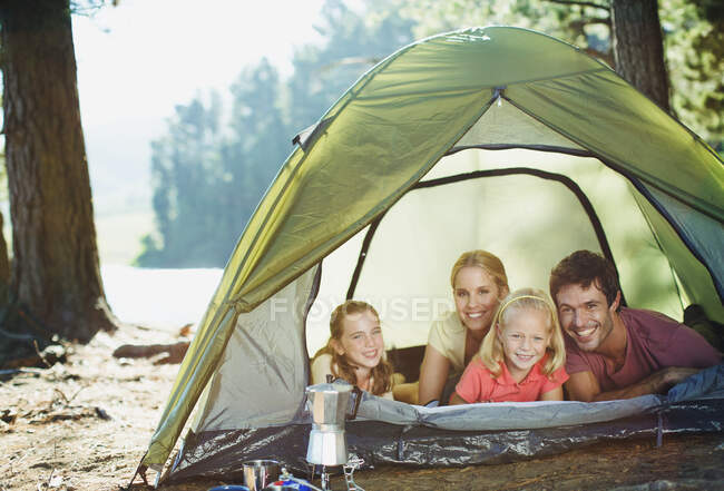 Famille souriante à l'intérieur de la tente dans les bois — Photo de stock
