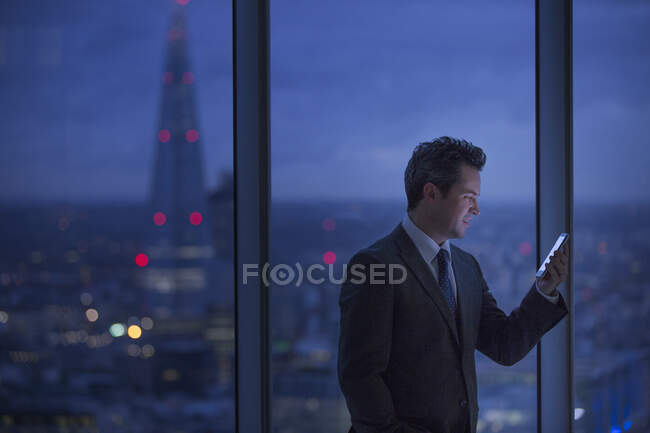 Businessman at urban window at night — Stock Photo
