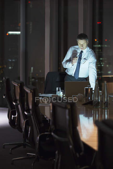 Empresario trabajando en el portátil en la sala de conferencias por la noche - foto de stock