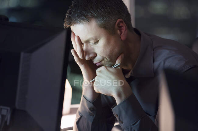 Hombre de negocios cansado trabajando hasta tarde en la computadora - foto de stock