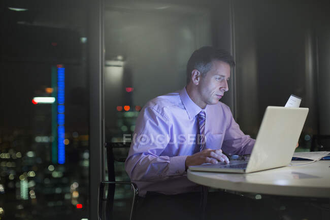 Businessman working at laptop in office at night — Stock Photo