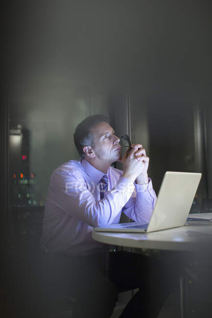 Психічний бізнесмен працює ноутбуком у офісі вночі. — стокове фото