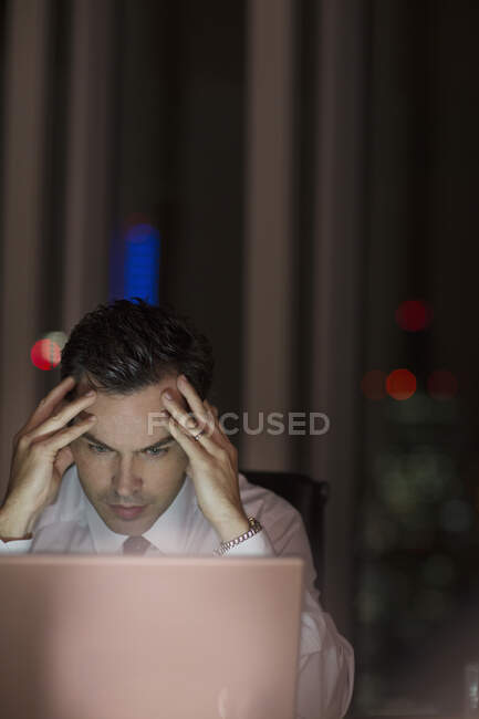 Uomo d'affari stressato che lavora fino a tardi al computer portatile — Foto stock