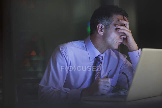 Uomo d'affari stanco che lavora fino a tardi al computer portatile — Foto stock