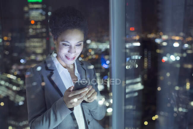 Бізнес-леді текстові повідомлення в міському вікні вночі — стокове фото
