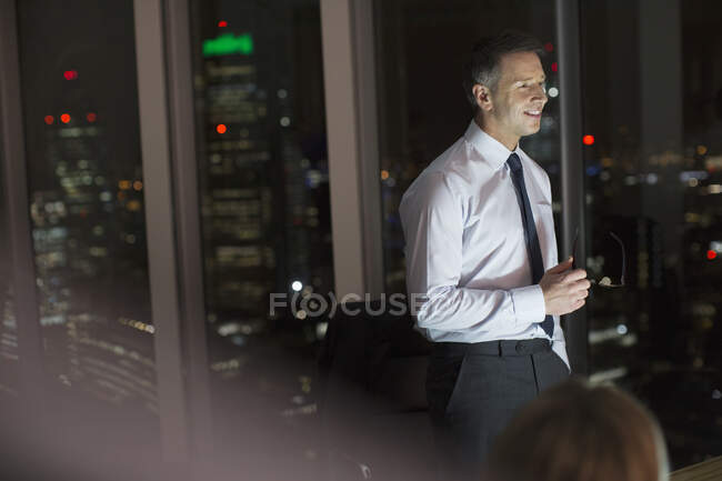 Empresario sonriendo en la oficina por la noche - foto de stock