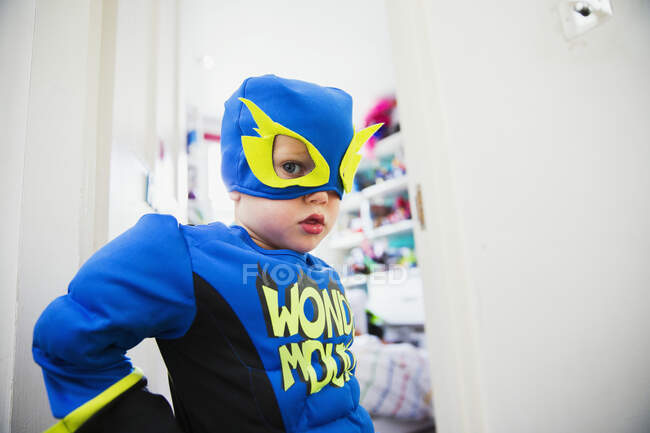 Junge im Superheldenkostüm posiert vor Tür zu seinem Zimmer — Stockfoto
