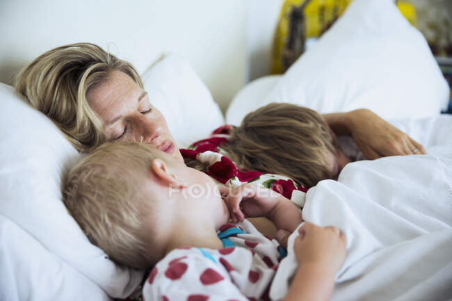 Madre con hijos durmiendo en la cama - foto de stock