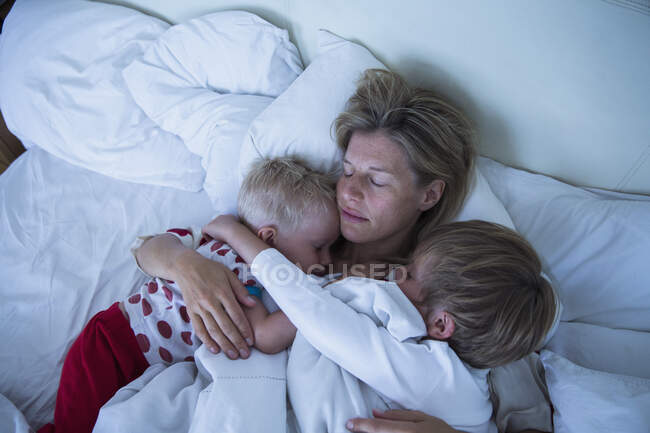 Мать с сыновьями, спящими в постели — стоковое фото