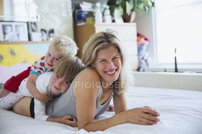 Портрет матері з синами в ліжку, що лежить один над іншим — стокове фото