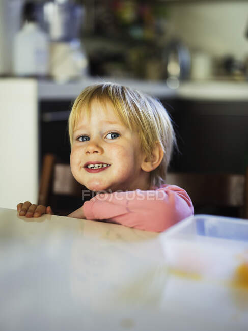 Garoto sorridente encostado ao balcão da cozinha — Fotografia de Stock