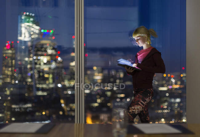 Бизнесвумен с цифровым планшетом работает допоздна в офисе в высотном здании — стоковое фото