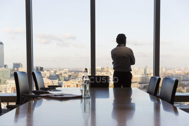 Empresário atencioso olhando para a janela da sala de conferências urbana — Fotografia de Stock