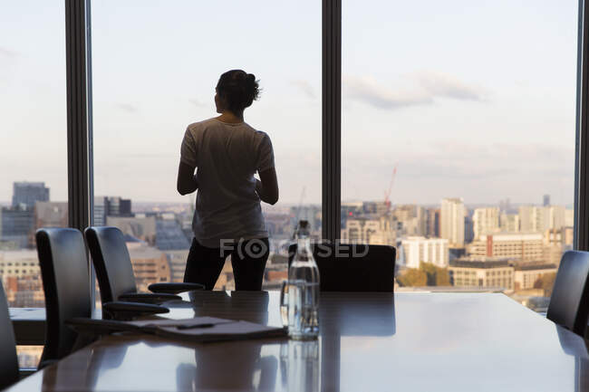 Thoughtful businesswoman looking out highrise office window — Stock Photo