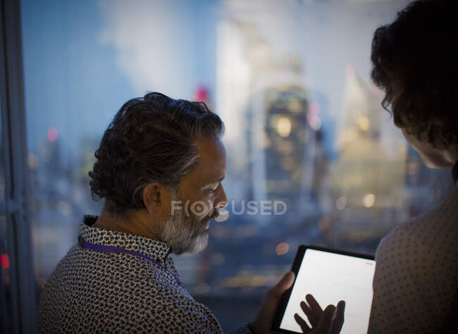 Empresários com tablet digital trabalhando até tarde na janela do escritório — Fotografia de Stock