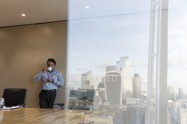 Businessman drinking coffee in highrise conference room, London, UK — Stock Photo