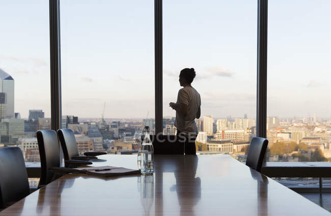 Thoughtful businesswoman at urban highrise office window — Stock Photo
