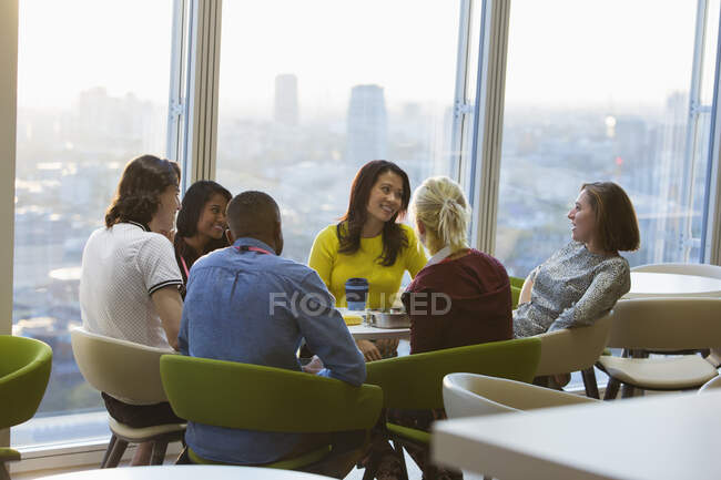 Smiling business people talking over lunch in urban cafeteria — Stock Photo