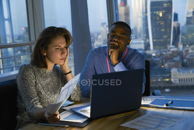 Gente de negocios trabajando hasta tarde en el portátil en la oficina urbana de rascacielos - foto de stock