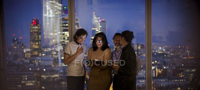 Uomini d'affari con tablet digitale che lavorano fino a tardi alla finestra del grattacielo — Foto stock