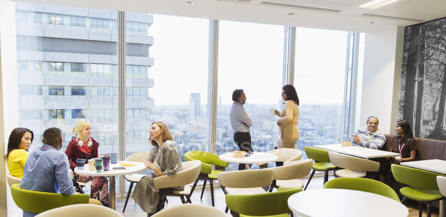 Business people talking and drinking coffee in highrise cafeteria — Stock Photo