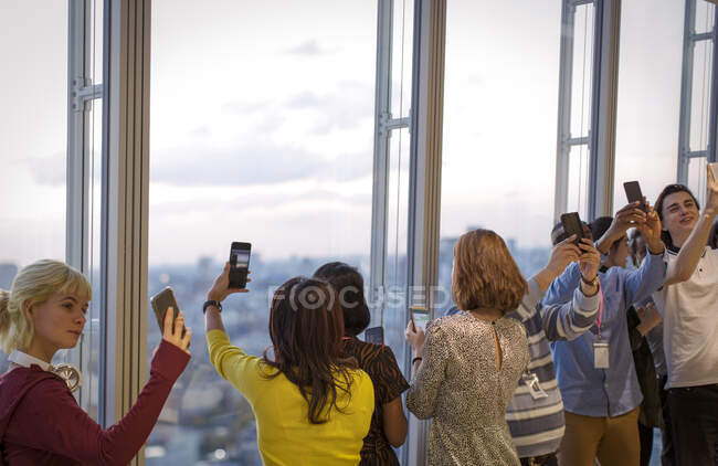 Business people taking selfies at highrise office window — Stock Photo
